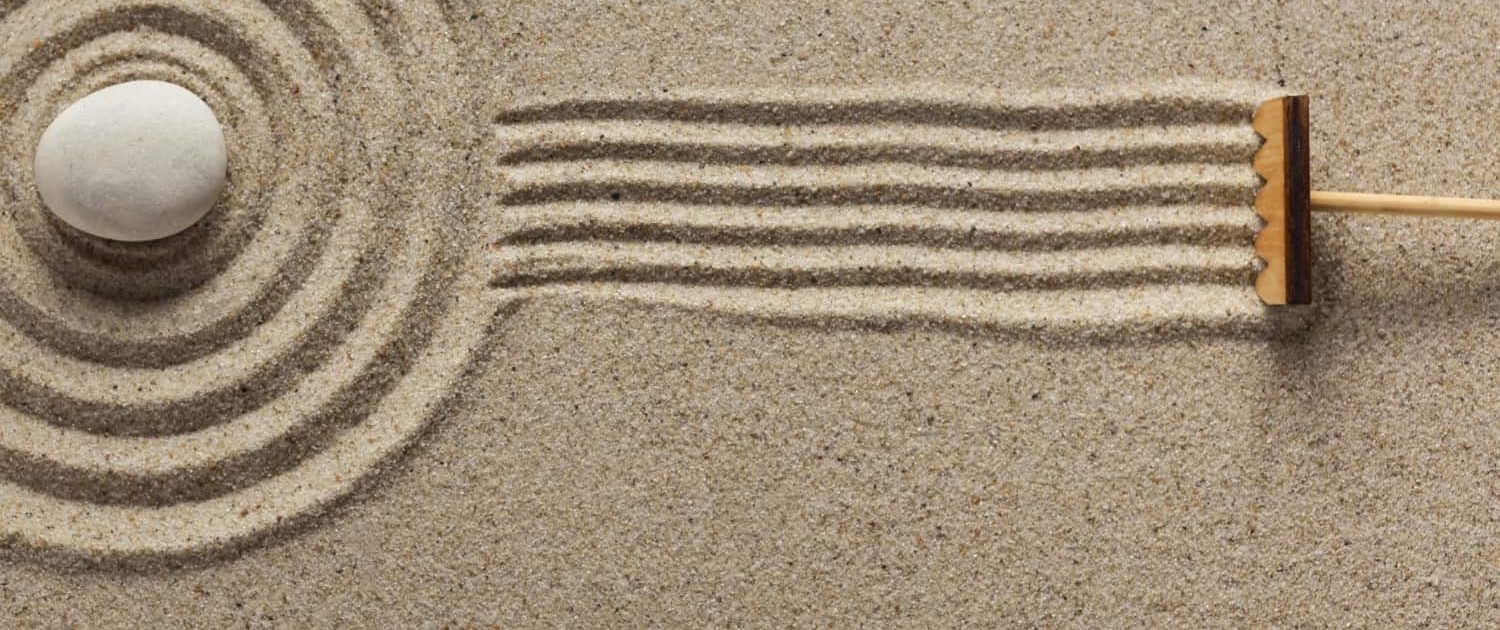 A rake creates fresh lines in a Zen-style sand garden