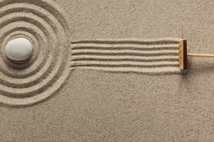 A rake creates fresh lines in a Zen-style sand garden