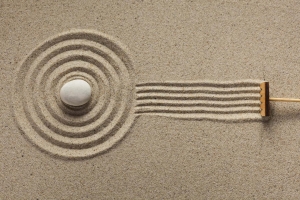 A rake creates fresh lines in a Zen-style sand garden