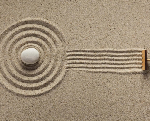 A rake creates fresh lines in a Zen-style sand garden