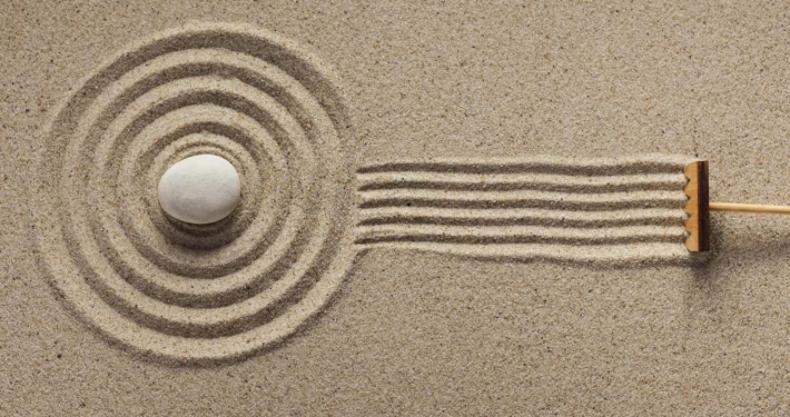 A rake creates fresh lines in a Zen-style sand garden