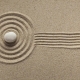 A rake creates fresh lines in a Zen-style sand garden