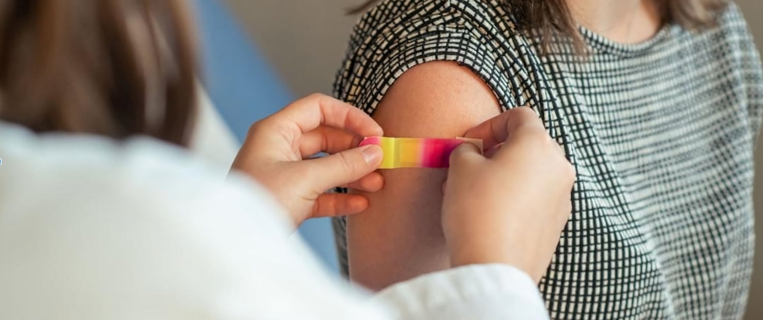 A doctor puts a bandaid on a patient's arm after giving them a vaccination