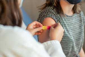 A doctor puts a bandaid on a patient's arm after giving them a vaccination