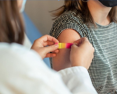 A doctor puts a bandaid on a patient's arm after giving them a vaccination