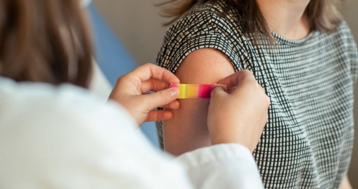 A doctor puts a bandaid on a patient's arm after giving them a vaccination